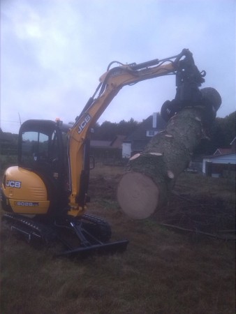 Boomstammen stapelen met sorteerknijper op minigraver